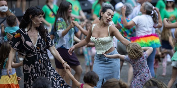 ARTS - Crowd of people dancing and smiling with a focus on two adults and two children in front dancing together.