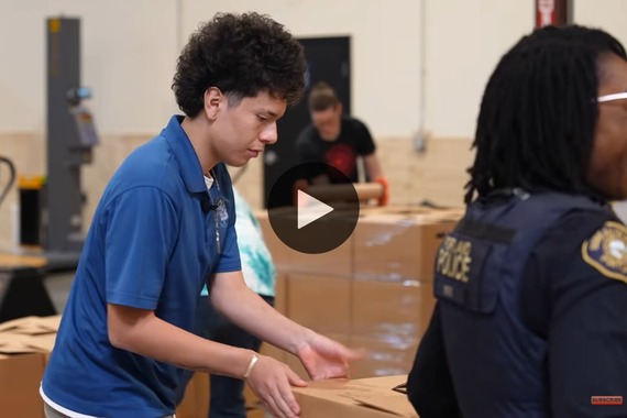 A high school student helps box up food donations at Sunshine Division warehouse