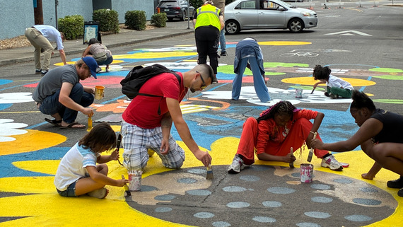 Community members repainting the "Emergence of Joy" street mural during the Lower Albina Block Party.