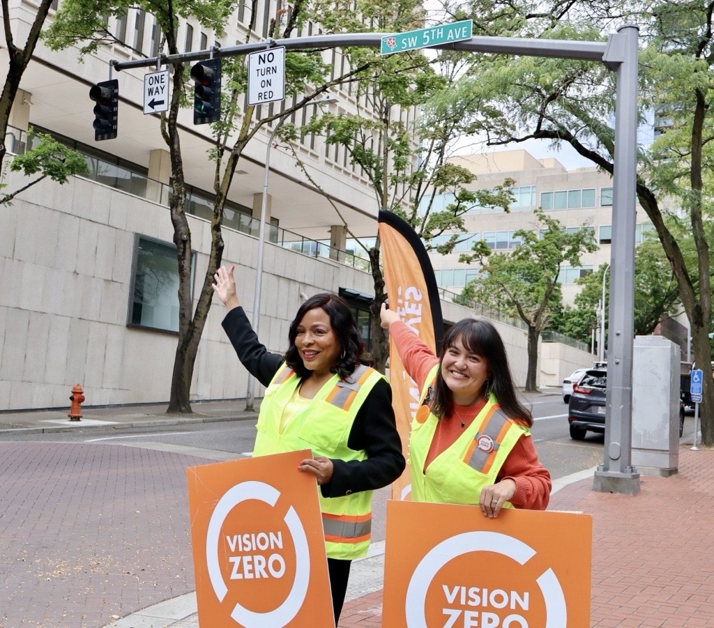 Councilors Loretta Smith and Tiffany Koyama Lane holding Vision Zero signs by a “No Turn on Red” sign