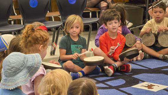 ARTS - A small group of young students sit on a carpeted floor with various instruments in-hand to celebrate Arts in Education Week.