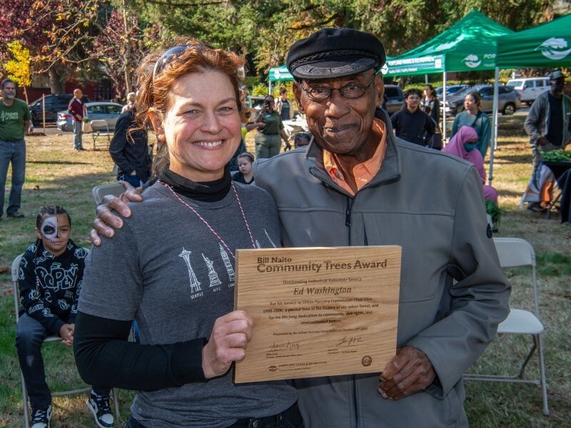 Two people holding wooden plaque that says Bill Natio Award Winner