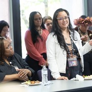 A person smiles while speaking in front of people