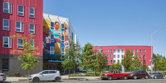 A multi-story housing development with a colorful mural and red and white siding