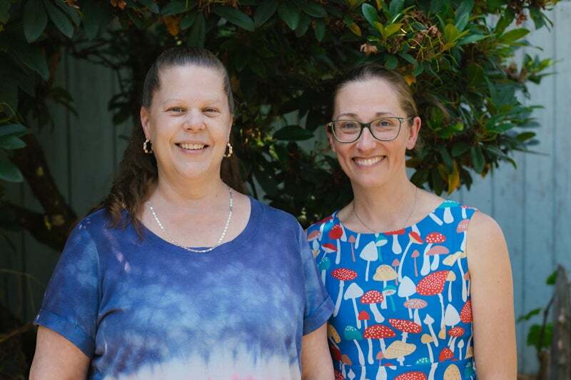 Two women stand next to each other, smiling at the camera, for a story about home sharing