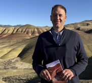 Secretary Read holding the 2025-2026 Oregon Blue Book at the Painted Hills