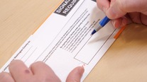 Voter signing ballot envelope. 