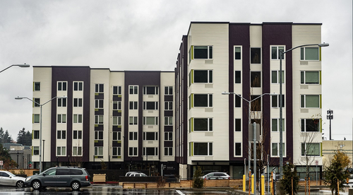 Fuller Road apartments, image of five story apartment complex with white and brown sections, in the foreground there's a parking lot.