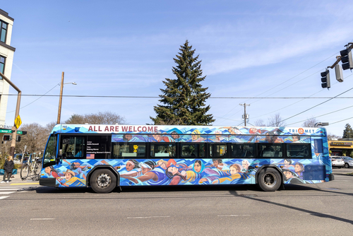 Image of the side of a bus with various women's faces collectively making a tsunami-like wave.