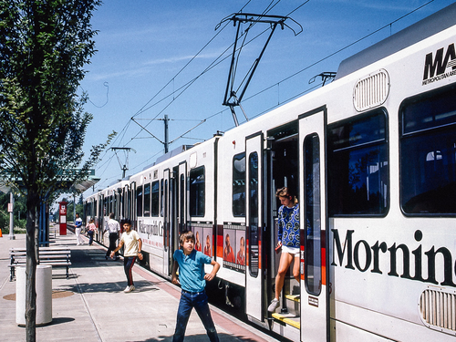 Image from 1986 of people getting off a Type 1 MAX train at Gresham City Hall on a sunny day.