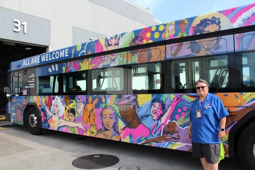 Colorful design on a bus celebrating Pride Month and a bus operator posing with it