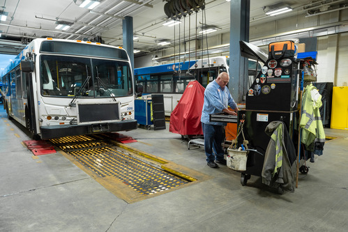 Bus in a garage next to a mechanic