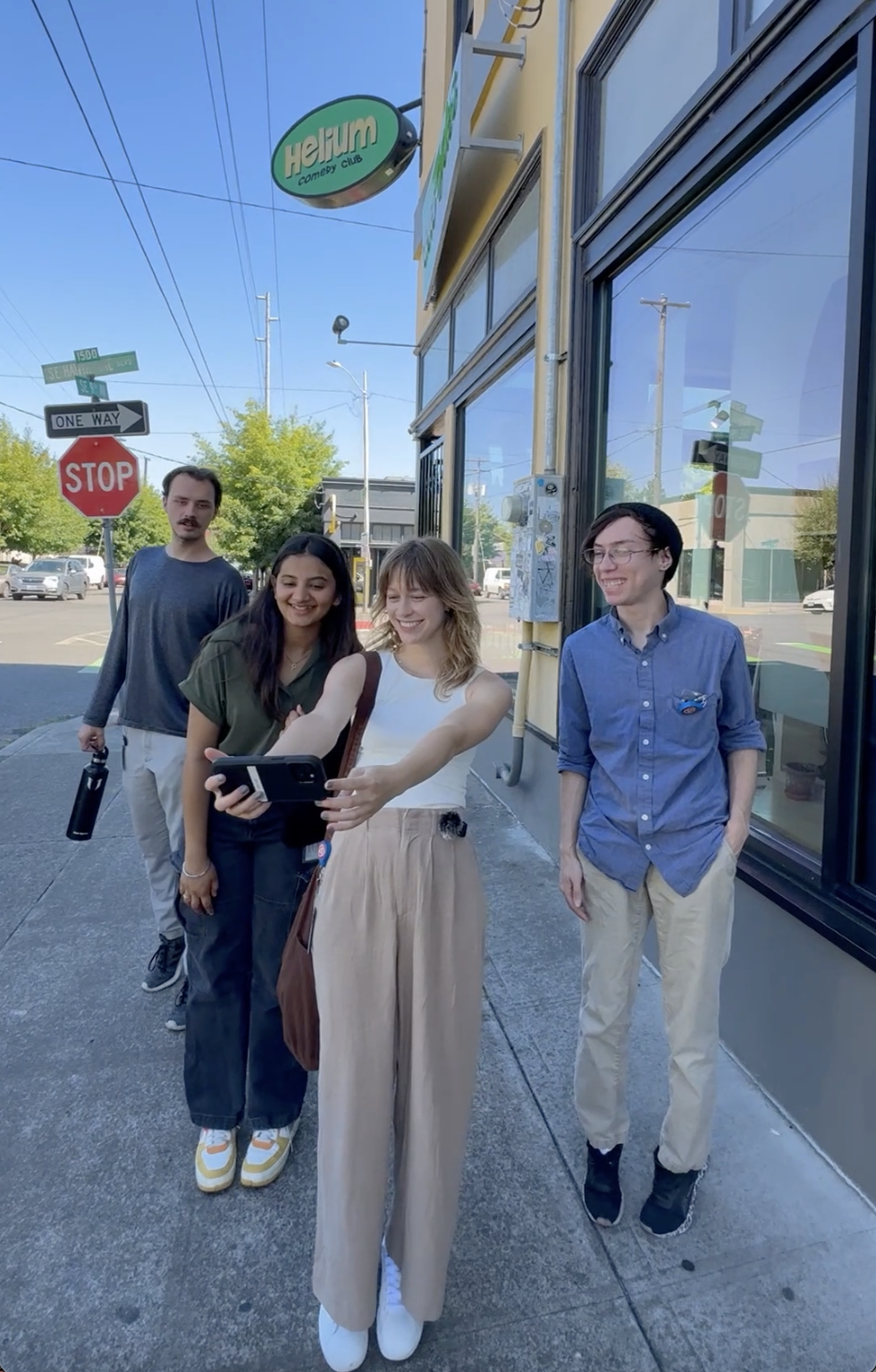 Four people taking a selfie in front of Helium Comedy Club