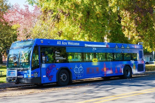 TriMet 2024 Native American History bus has a blue background and displays colorful, tribal artwork in a design created by Don Bailey