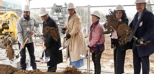 Image of six people, including TriMet General Manager Sam Desue Jr., smiling and shoveling dirt.