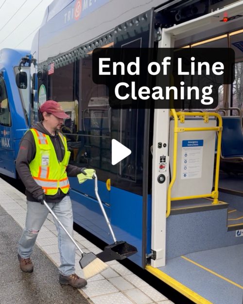 TriMet employee carrying cleaning supplies and about to board a train