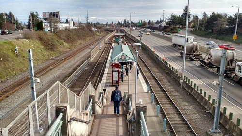 Image of the NE 82nd Ave MAX Station in Northeast Portland, with riders waiting for their train.