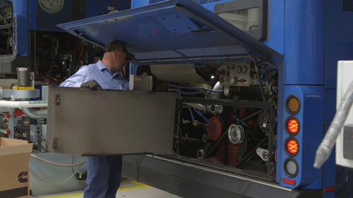 Image of a TriMet bus mechanic installing a panel on the back of a bus at the Powell Operations Facility