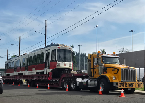 Image of a MAX Type 1 light rail vehicle on the back of a truck with a banner reading "Oversize Load"