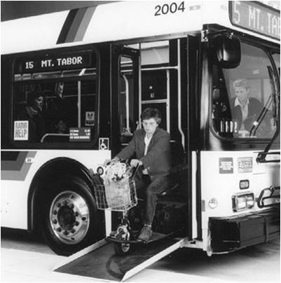 A TriMet bus with a deployed ramp at its entrance, allowing a person with a mobility aid to board or exit the vehicle