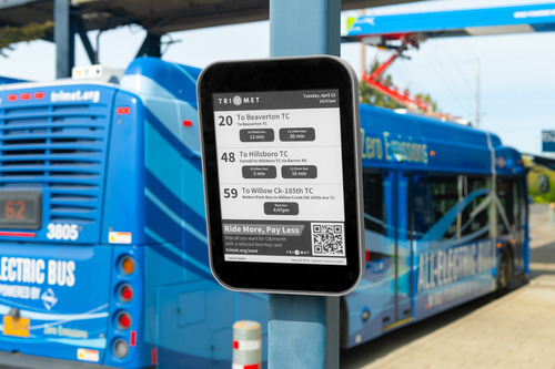 Image of a TriMet ePaper digital display at the Sunset Transit Center, with a zero-emissions bus in the background