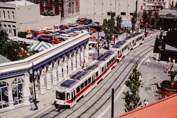 Train 124 traveling near the Skidmore Fountain area in downtown Portland. The train is moving alongside a historic colonnade structure,.