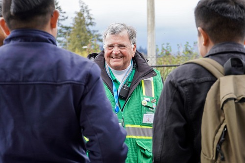 Image of a TriMet On-Street Customer Service representative, a man wearing a green safety vest, speaking with riders at the Gateway Transit Center