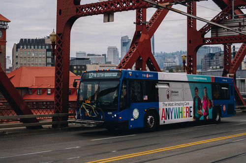 Image of a blue TriMet Line 17-Holgate/Broadway bus driving across the Broadway Bridge, with Portland's Union Station in the background
