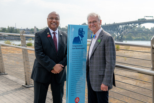 Image of TriMet General Manager Sam Desue Jr. and former Congressman Earl Blumenauer standing next to a blue commemorative plaque