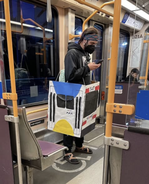 rider on a MAX train is dressed in a handmade cardboard costume shaped like a TriMet light rail car