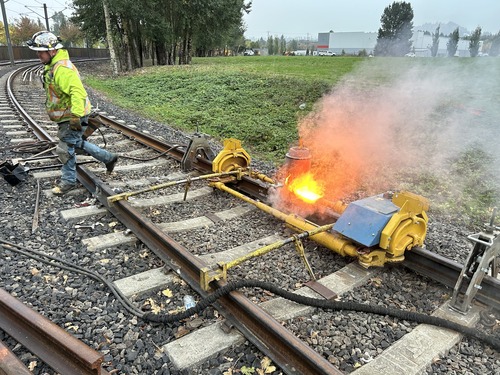 A worker uses a machine to weld track components on TriMet MAX light rail