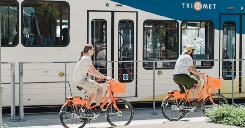 Picture of two cyclists riding parallel to a TriMet MAX Light Rail train