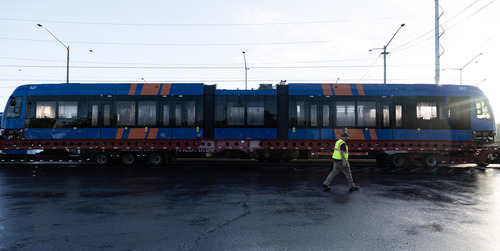 A long, blue-and-orange MAX Type 6  train sits on a red transport trailer