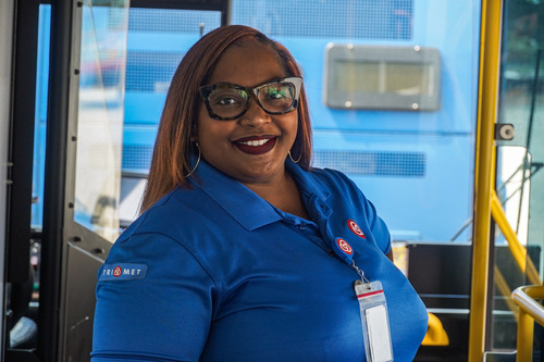 Bus driver inside a TriMet bus smiling at the camera