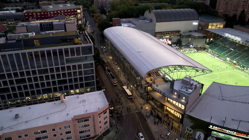 Aerial shot of a MAX and bus on Southwest 18th Avenue, alongside Providence Park in Portland.