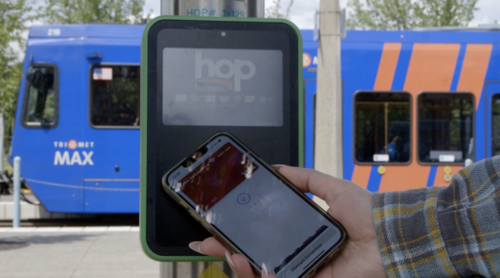 rider tapping their phone's mobile wallet on a Hop reader 
