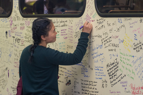 A woman writes a message on the side of a MAX Type 1 train at its retirement
