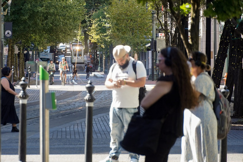 Riders wait for an approaching TriMet MAX train at the Yamhill District MAX Station