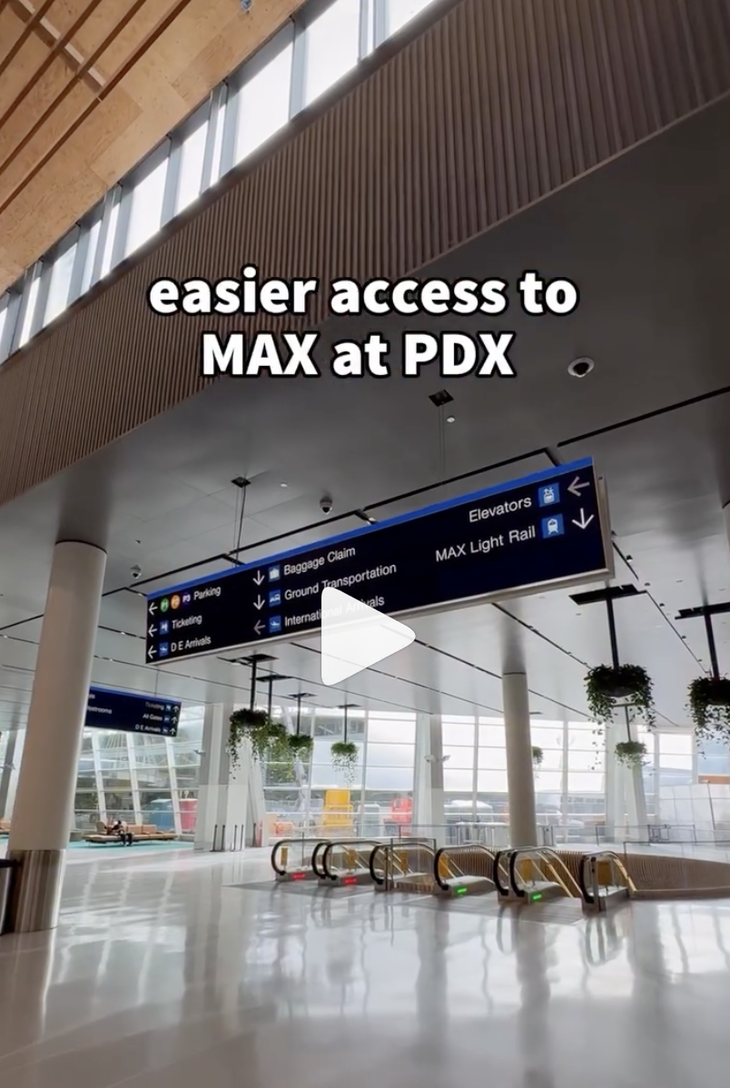 Interior of PDX airport with signs pointing to MAX light rail access