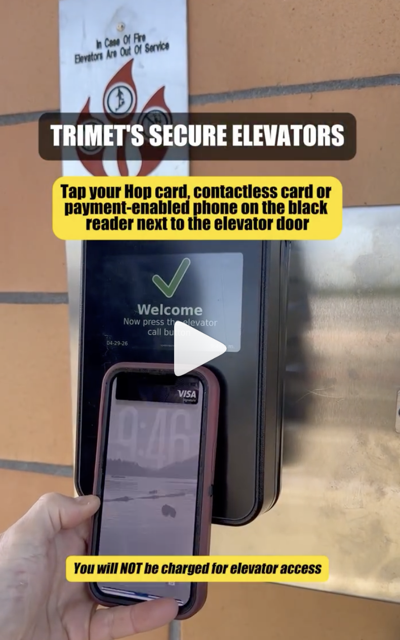 Hand holding a phone up to a TriMet elevator access reader with instructions on how to unlock the elevator.