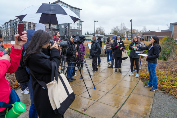 Around 18 people, some with cameras, learning about stormwater pollution prevention at Sunset Neighborhood Park