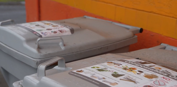 Gray compost bins outside against a wall