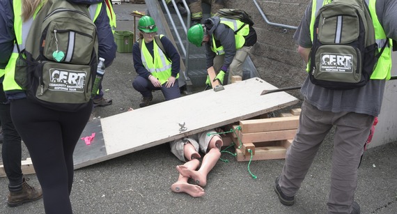 CERT program participants doing a training while being watched by firefighters