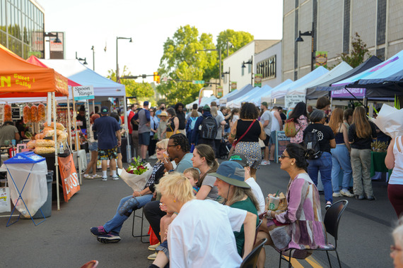 Renton Farmers Market with people seated watching the entertainment and people walking in the background