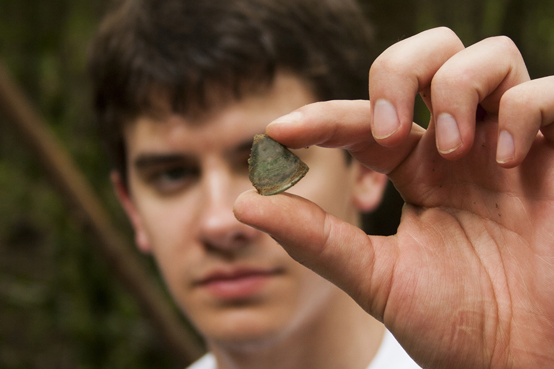 SCDNR archaeology field school student holds up knapped bottle glass