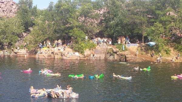 swimmers on floaties in a quarry surrounded by rocks