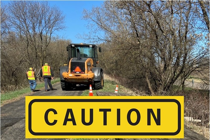 Caution sign with maintenance crew in background