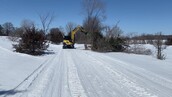 machine cutting trees on a snowy trail