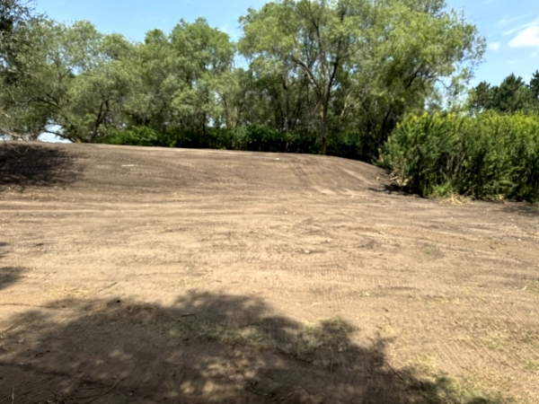 berm of dirt with trees in background