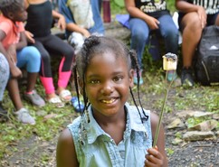 Child roasting a marshmallow at Hidden Falls summer camp.